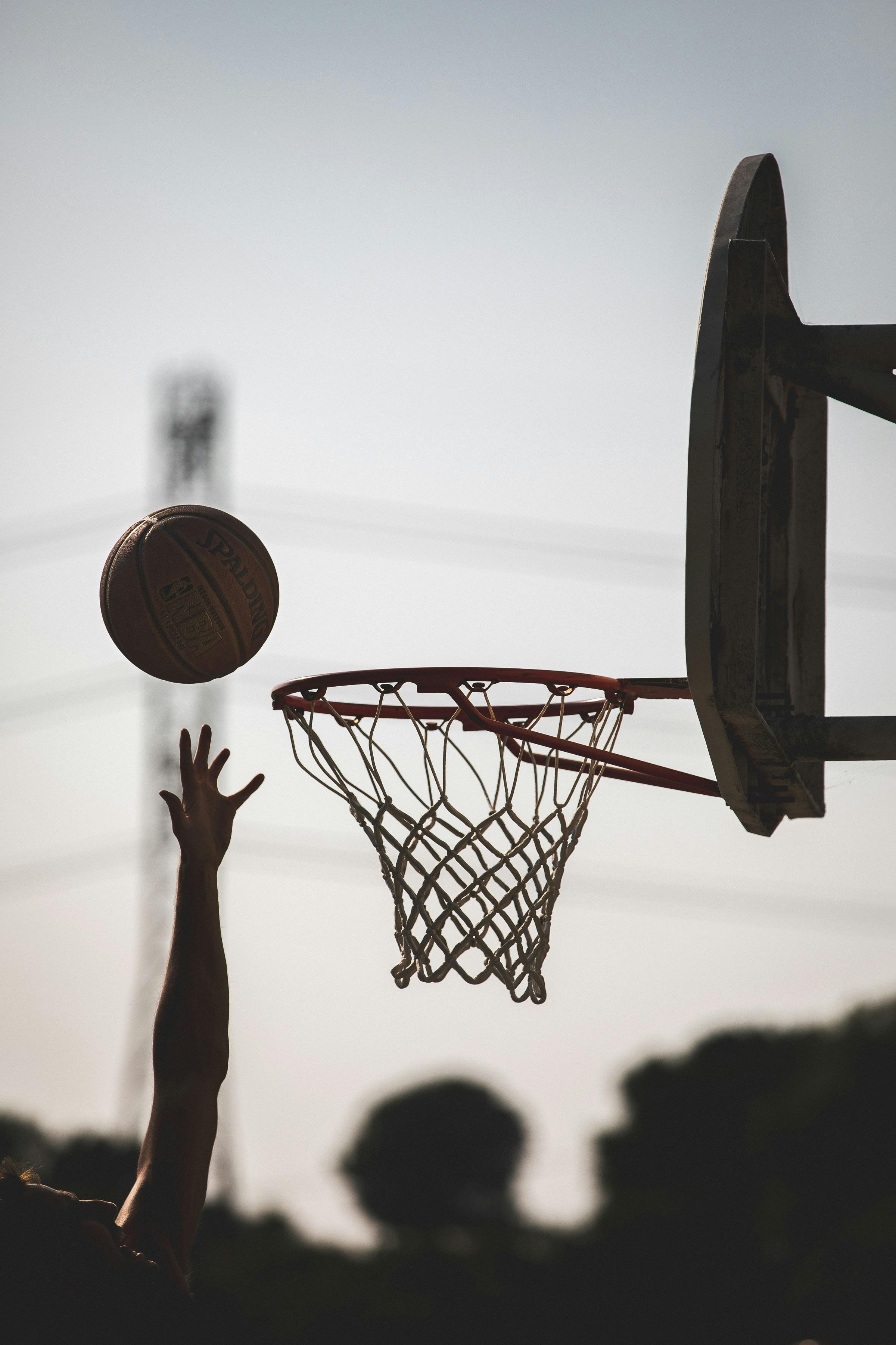 Outdoor basketball shot arcing toward the hoop at golden hour
